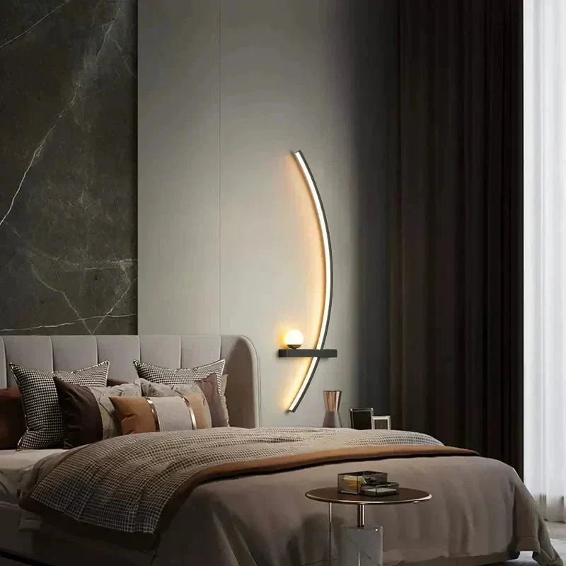 Modern bedroom with a bed, decorative pillows, and wall-mounted lamp.
