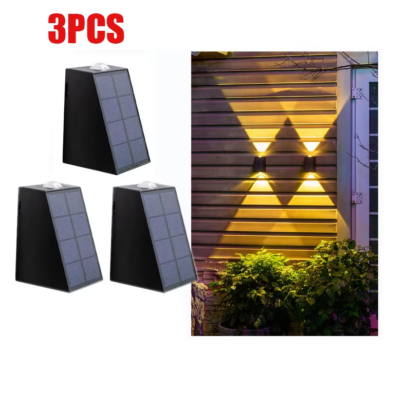 Three solar wall lights with a fourth one illuminated on a white background.